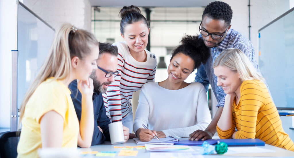 A team of individuals from diverse ethnicities, genders, and age groups collaborating on a shared goal in a modern workplace.