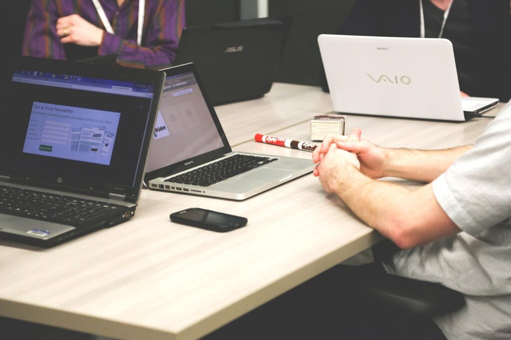 An image of a team working around a computer with various collaboration tools